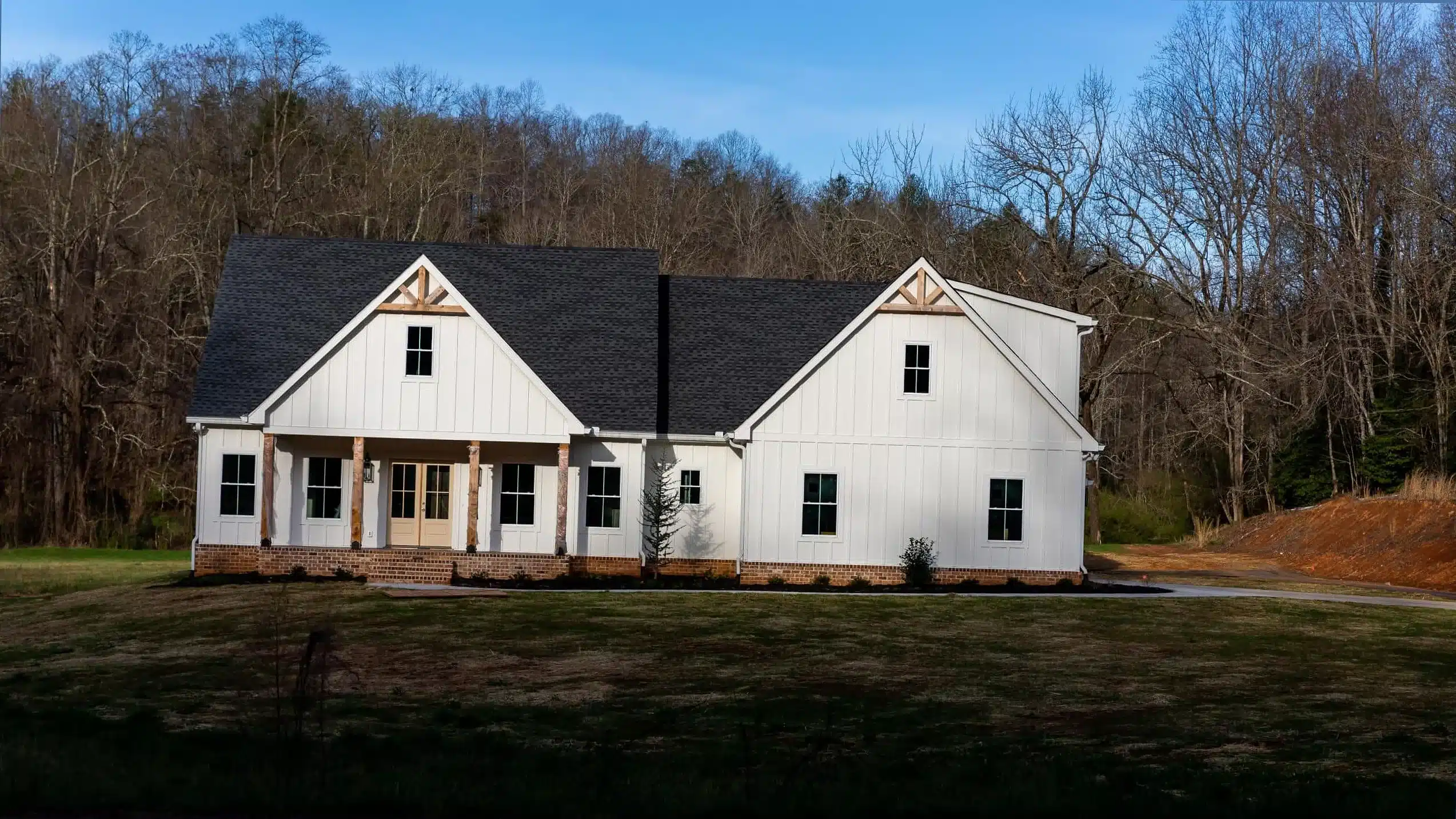 A white custom farmhouse with cedar gable accents and a deep front porch, built by Lanier Home Builders in North Georgia